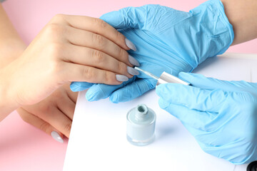 Nail care procedure on pink background, close up