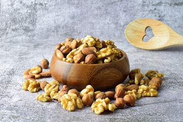 Assortment of nuts, walnuts, hazelnut and almond on a stone base and in a wooden bowl.
