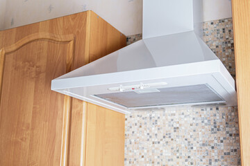 Ceiling metal white cooker hood above the kitchen stove. Modern kitchen appliances. A device for...