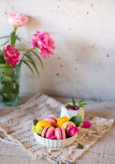 Obraz na płótnie Canvas Good morning. Delicious macarons desserts are served on the table in the morning for breakfast. Beautiful light still life with a rose highlight. Baking for breakfast on a light table with copy space