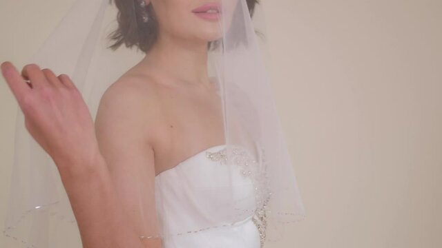 Close-up portrait of a bride in a dress with a veil that covers her head. Happy wedding day.