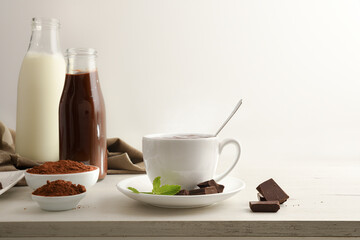 Obraz na płótnie Canvas Hot chocolate cup with chunks and powder and bottles isolated