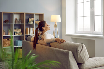 Woman uses chance to relax, unwind and get some peace of mind on comfy couch at home. Happy lady...