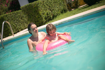 Loving brothers swimming in swimming pool. Long-haired boy and teenager playing together. Leisure, family, party concept