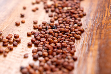 Red quinoa seeds on wooden background. Rustic wood bowl