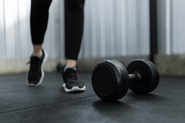 exercise concept The black rubber coated round dumbbell lying on the gym ground in front of the...
