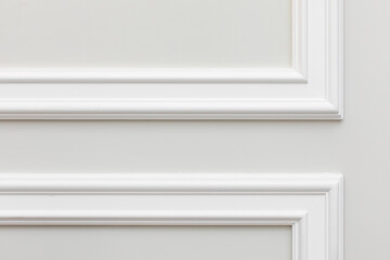 Close-up detail of classic white interior with installed wall panels, decorated with angular moldings. Final stage of finishing works in the apartment.