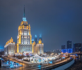 Fototapeta na wymiar Illuminated high-rise stalinist building near river at winter night in Moscow, Russia. Historic name is Hotel Ukraine.
