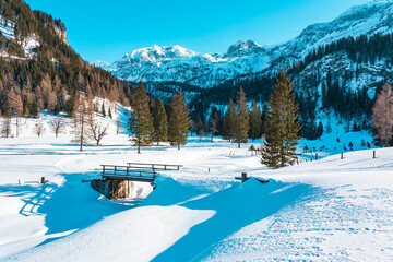 The cross-country trail through the area of ​​Gnadealm Obertauern, Austria goes over bridges and past beautiful snow-capped mountains