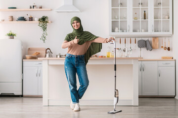Muslim woman showing thumbs up cleaning floor with spray mop