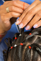 photography of a hairstyling procedure in the beauty salon. woman making hair braids to a little girl. kids hairstyles