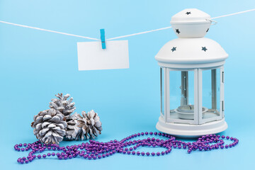 White lantern with candle inside and Christmas decoration on blue background. Copy space.