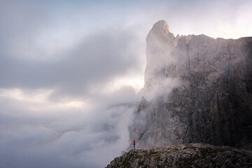 man standing on the edge of a cliff in the mountains of pale di san martino in the dolomites surrounded by clouds