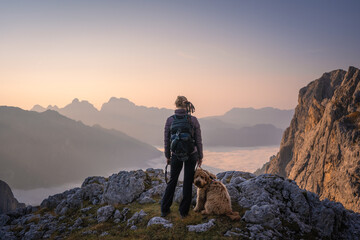 hiker on top of a mountain of pale di san martino in the dolomites enjoying sunrise 