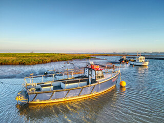 Small fishing boats moored at low tide at Stone Creek inlet, Sunk Island, East Yorkshire, UK