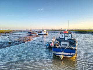 Fototapeta premium Small fishing boats moored at low tide at Stone Creek inlet, Sunk Island, East Yorkshire, UK