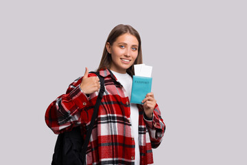 Traveler tourist fun woman in checkered shirt hold on passport with tickets show thumb up like gesture