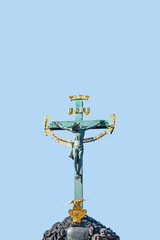 Fototapeta na wymiar Cover page with Statue of Crucifixion of Jesus at the Charles Bridge in Prague, Czech Republic, at blue sky solid background. Concept of religious and historical architecture heritage.