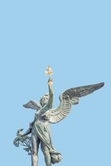 Cover page with statue of beautiful angel with wings at the top of column on the Cechuv Most Bridge in Prague, Czech Republic, portrait, details, at blue sky solid background with copy space.