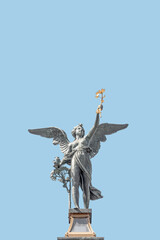 Cover page with statue of beautiful angel with wings at the top of column on the Cechuv Most Bridge in Prague, Czech Republic, portrait, details, at blue sky solid background with copy space.