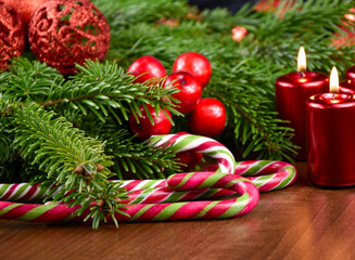 Candy cane with spruce twig and burning candles on the table stock images. Beautiful christmas decoration with red candles stock photo