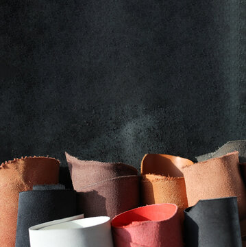Close-up pieces of the leather material on the working desk in the leather workshop. Vertical banner with spece for text
