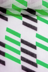 Fototapeta na wymiar Texture. Background. Template. White silk fabric with green and black geometric rhombus shapes.