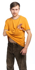 A man in a torn orange T-shirt and old corduroy brown trousers stuck his hand into the hole in the T-shirt and looks at us in surprise. isolated, white background