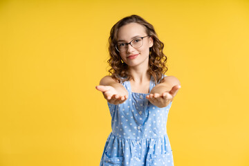 portrait of a beautiful girl in a blue summer dress with white polka dots. model in the studio. yellow background
