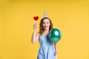 portrait of a beautiful girl with donut, candy. teenager celebrates, birthday, new year, christmas. yellow background