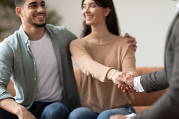 Happy couple shaking hands with therapist at office