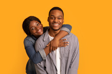 Obraz premium Portrait of young cheerful black couple hugging and smiling at camera