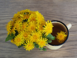 Dandelion grass flowers, herbal tea on wooden table, flat layout. Medicinal plant taraxacum with vitamins for use in food, medicine, homeopathy and cosmetology