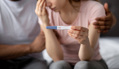 Young multiracial couple with positive pregnancy test feeling upset, facing unplanned childbearing, having problems
