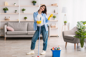 Portrait of holding woman cleaning floor singing holding mop