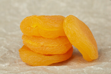 Dried apricots lie on crumpled paper in a stack, close-up photo