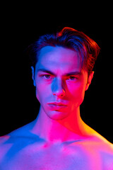 Handsome young man's portrait isolated on dark studio background in pink neon, Concept of human emotions, facial expression