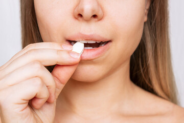 Naklejka premium Cropped shot of a young caucasian blonde woman taking a pill. The girl takes medications isolated on a white background. Treatment of the disease. Taking antibiotics