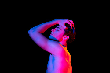 Gesture. Handsome young man's portrait isolated on dark studio background in pink neon, Concept of human emotions, facial expression