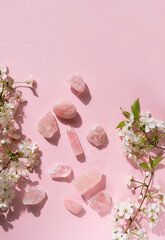 Rose quartz minerals set and white flowers on pink background. gemstones for esoteric spiritual relax practice, Magic Crystal Ritual, Witchcraft, open Chakra. Feng Shui, reiki therapy. top view - obrazy, fototapety, plakaty