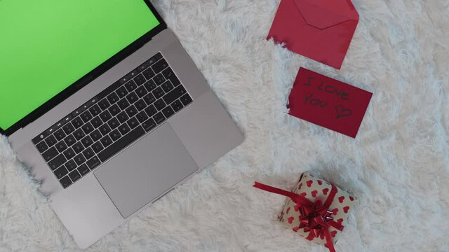 Computer su tappeto bianco con cuori e regali per san valentino