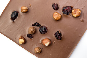 Hand crafted milk chocolate with hazelnuts, raisins and dried fruits on white background