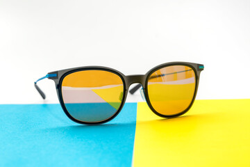 Conceptual elegant Sunglasses on blue, yellow and white background. Sun glasses summer accessories...