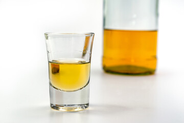 Alcoholic drink in a glass and bottle of brandy in the back on white table. Of strong alcoholic intoxication. The concept of alcohol dependence. Alcohol intoxication.

