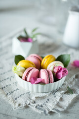 Good morning. Delicious macarons desserts are served on the table in the morning for breakfast. Beautiful light still life with a rose highlight. Baking for breakfast on a light table with copy space