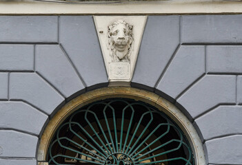 Detail of the façade of an old palace in the historic centre of Genoa decorated with a lion's head and an arched above-door, Liguria, Italy