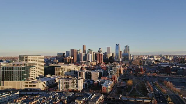 Drone Aerial View Of Denver Colorado Skyline Flying Back Passing The Confluence Modern Apartment Complex High Rise Building During Golden Hour Sunset.
