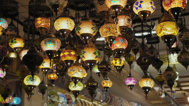 Traditional decorative hanging Turkish chandeliers for sale in a shop in a bazaar, slow motion. Eastern lights and colorful mosaic lamps with vivid colors