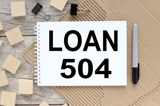 loan 504. text on a notebook that lies on a working wooden table near wooden blocks on torn paper