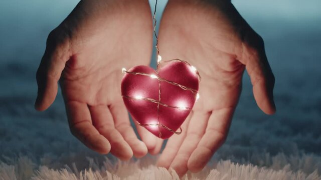 Mani tengono un cuore rosso luminoso per San Valentino
